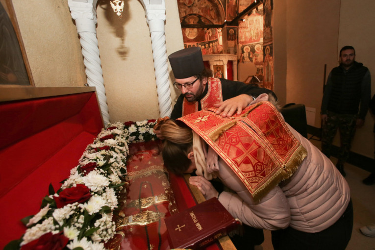 Sveštenik drži vernika nad kivotom