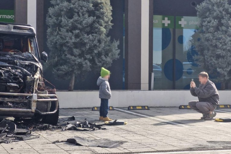 Ljudi se fotkaju ispred zapaljenog automobila