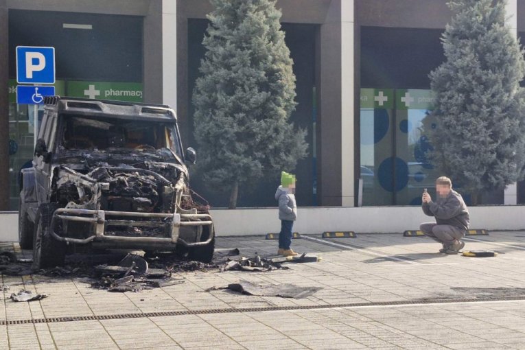 Ljudi se fotkaju ispred zapaljenog automobila